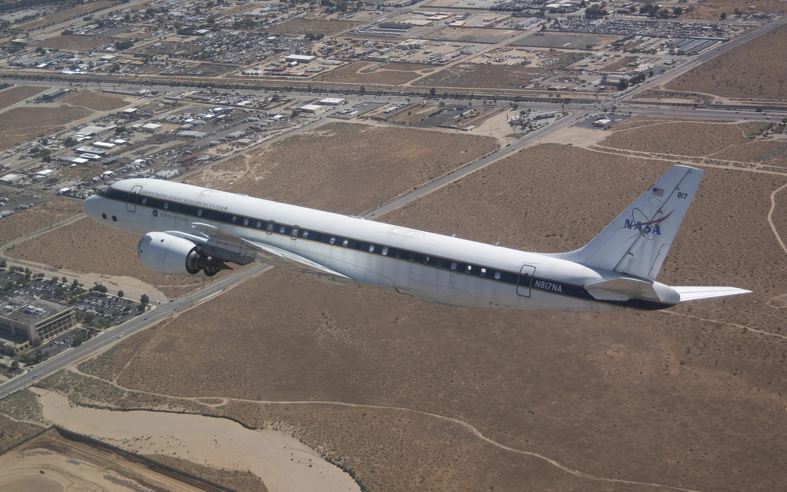 NASA&rsquo;s DC-8 airborne science aircraft flying low over the Antelope Valley, with the built valley floor, its streets and its rooftops below the wing